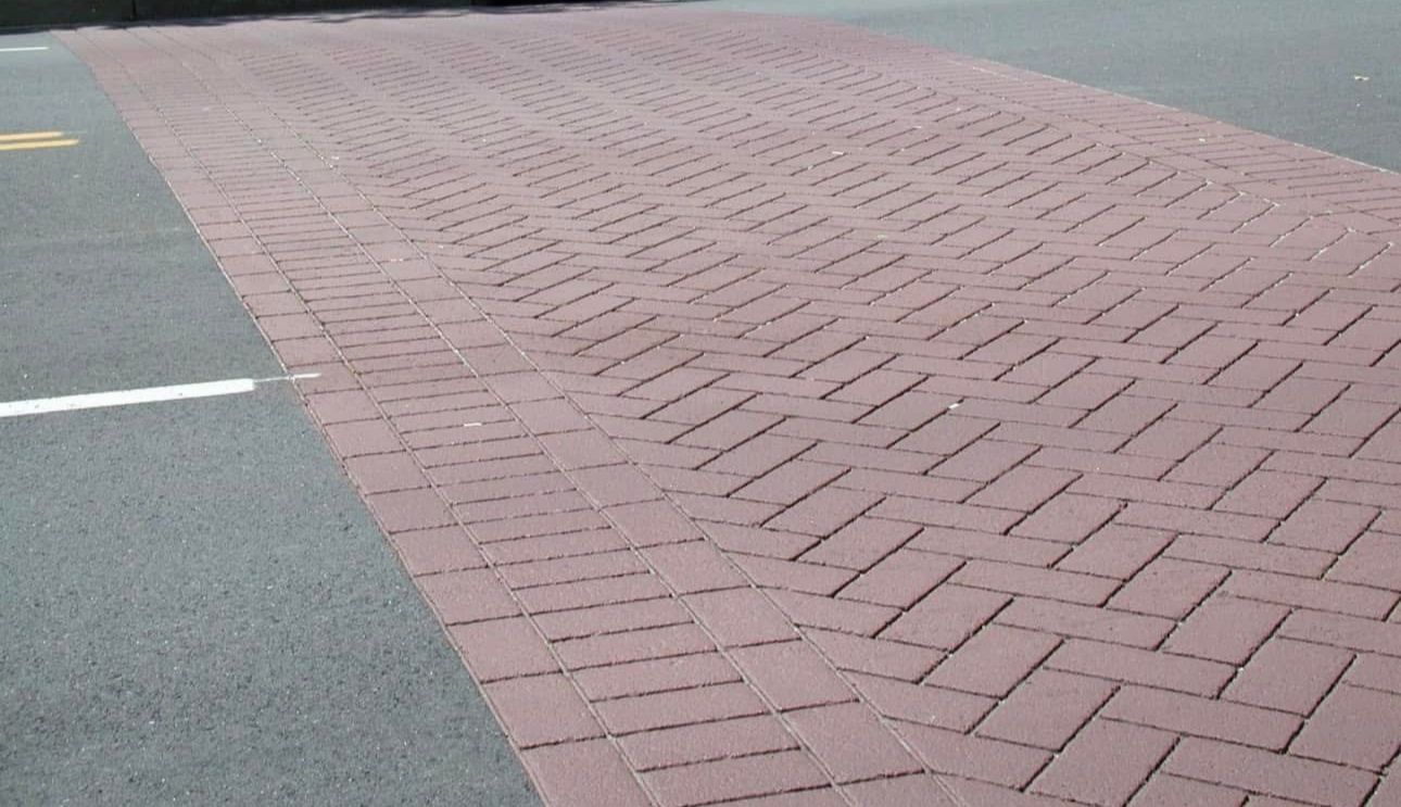 A close up of a brick walkway on the side of a road.