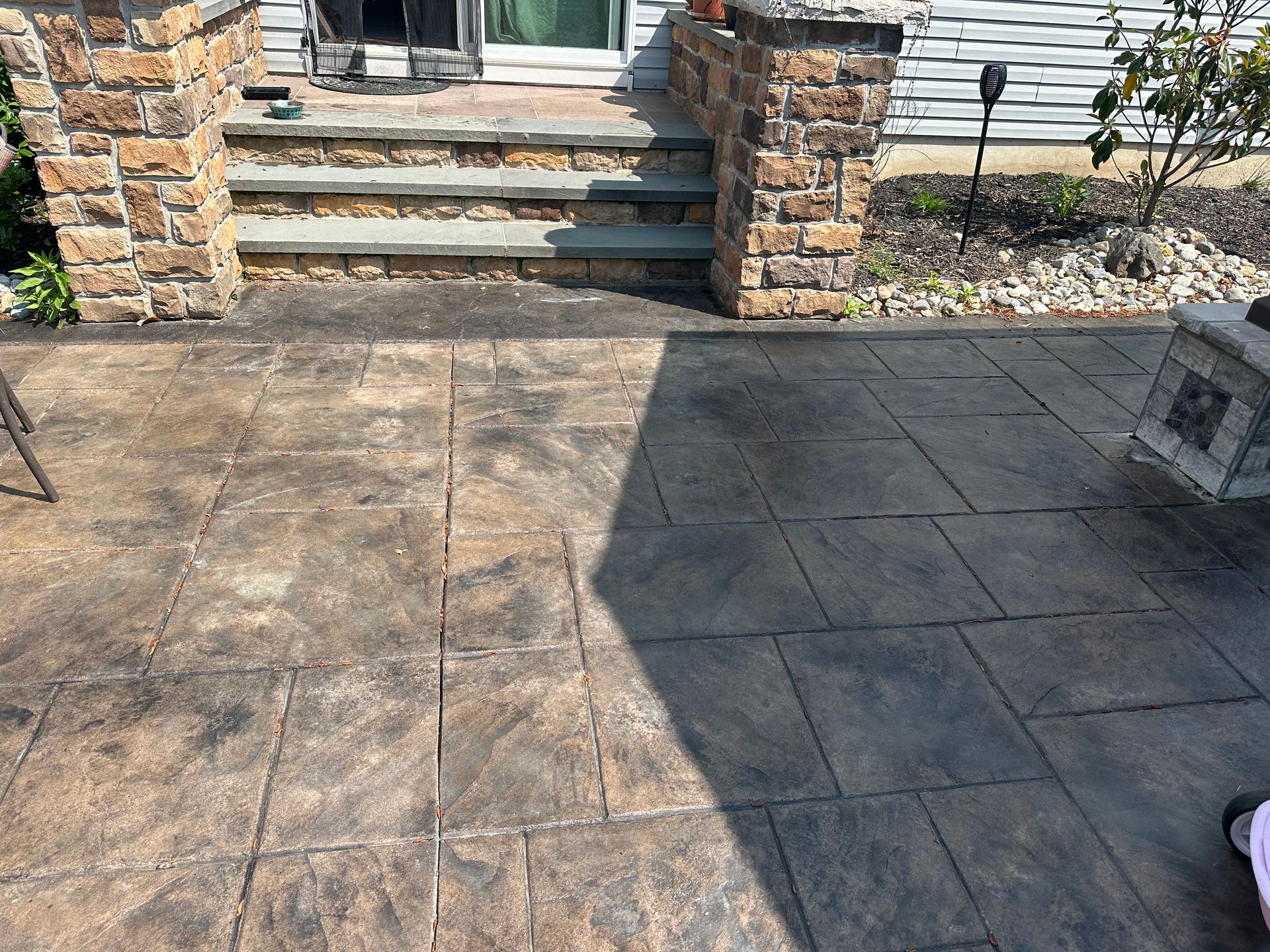 A patio with steps leading up to a door and a stone wall.