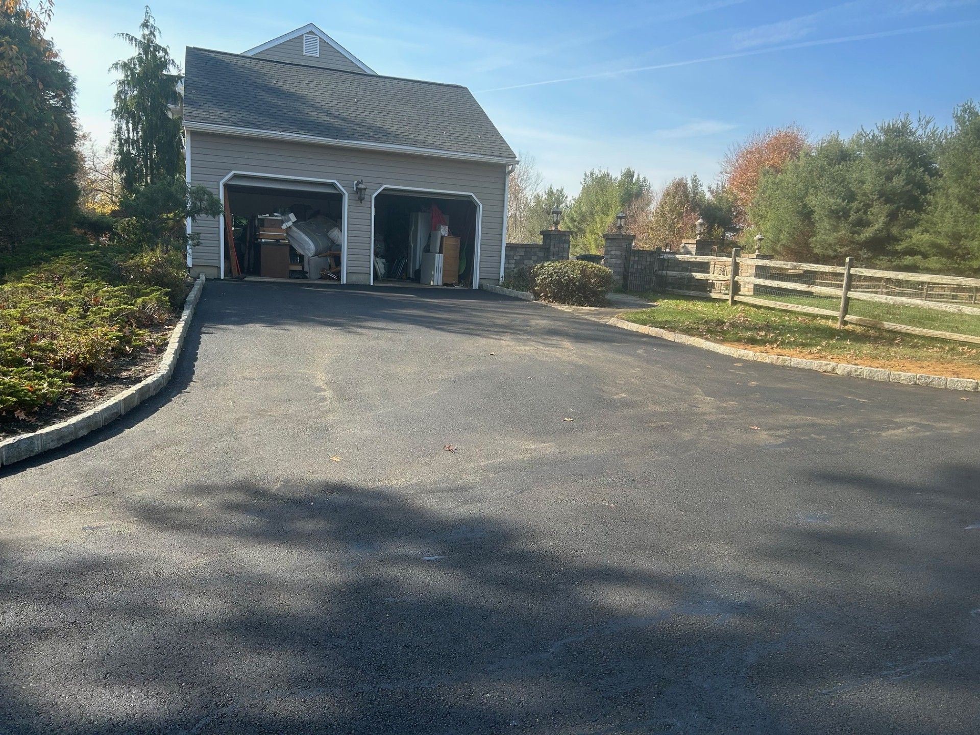A driveway leading to a garage with a fence in the background