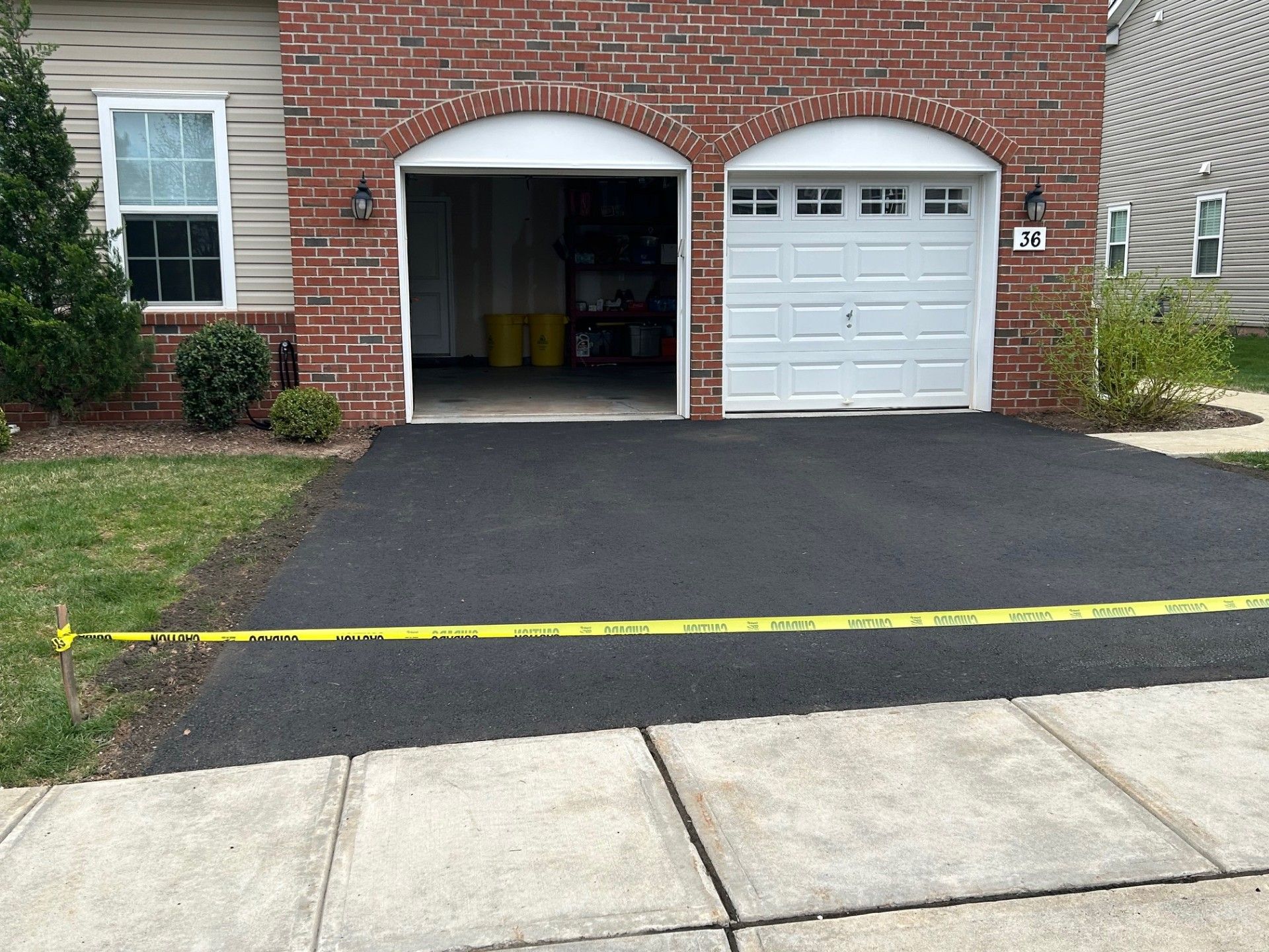 A brick house with a white garage door and a black driveway