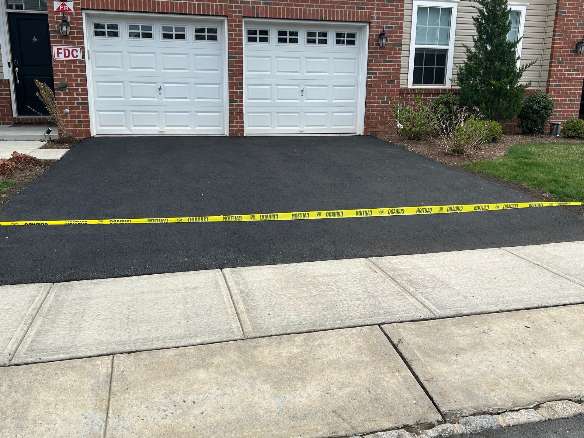 A brick house with two garage doors and a black driveway