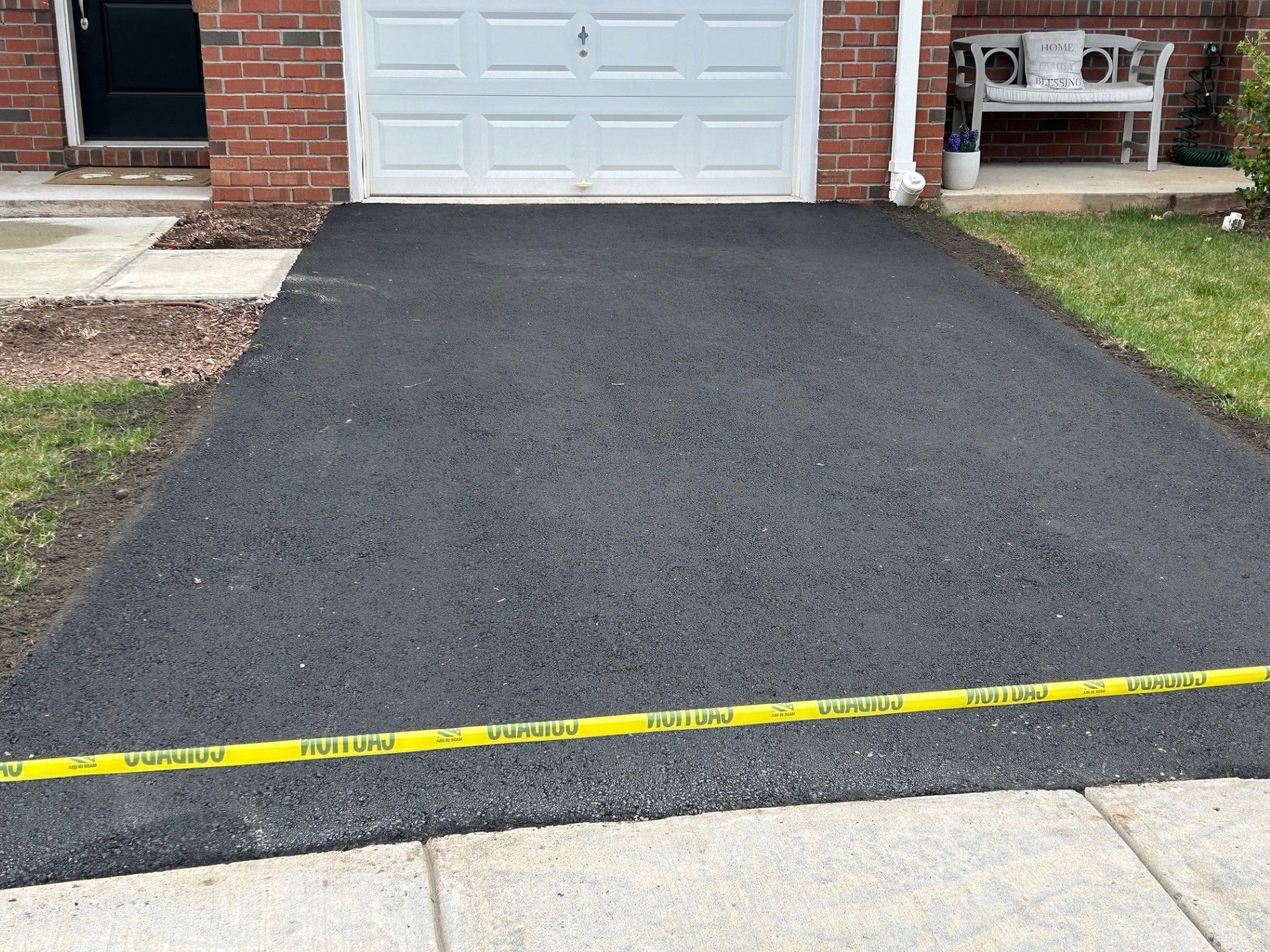 A driveway is being paved in front of a brick house.