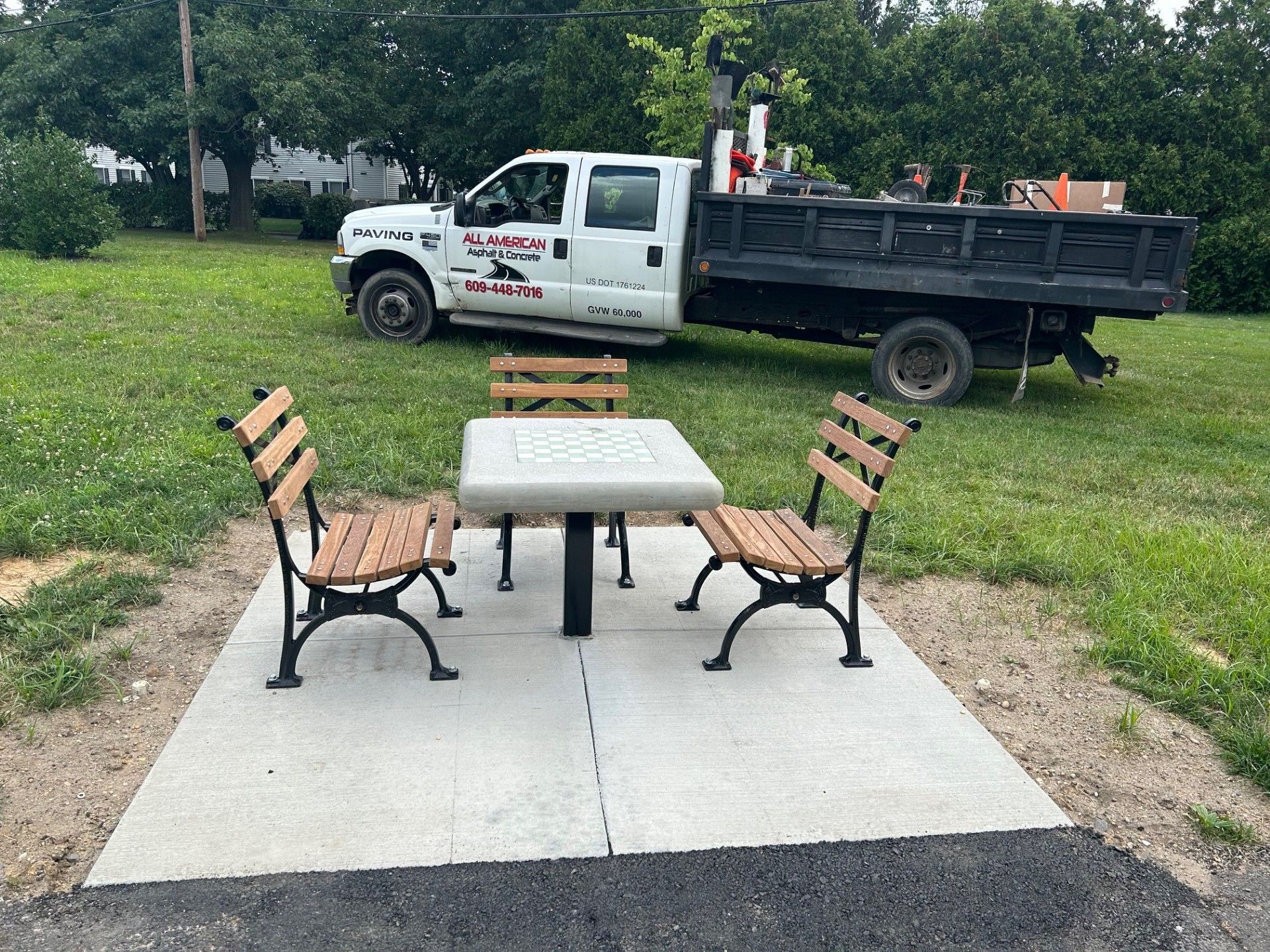 A dump truck is parked next to a picnic table and benches.
