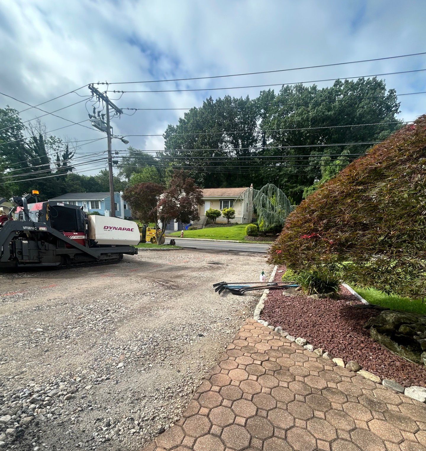A bulldozer is parked in a gravel lot in front of a house.