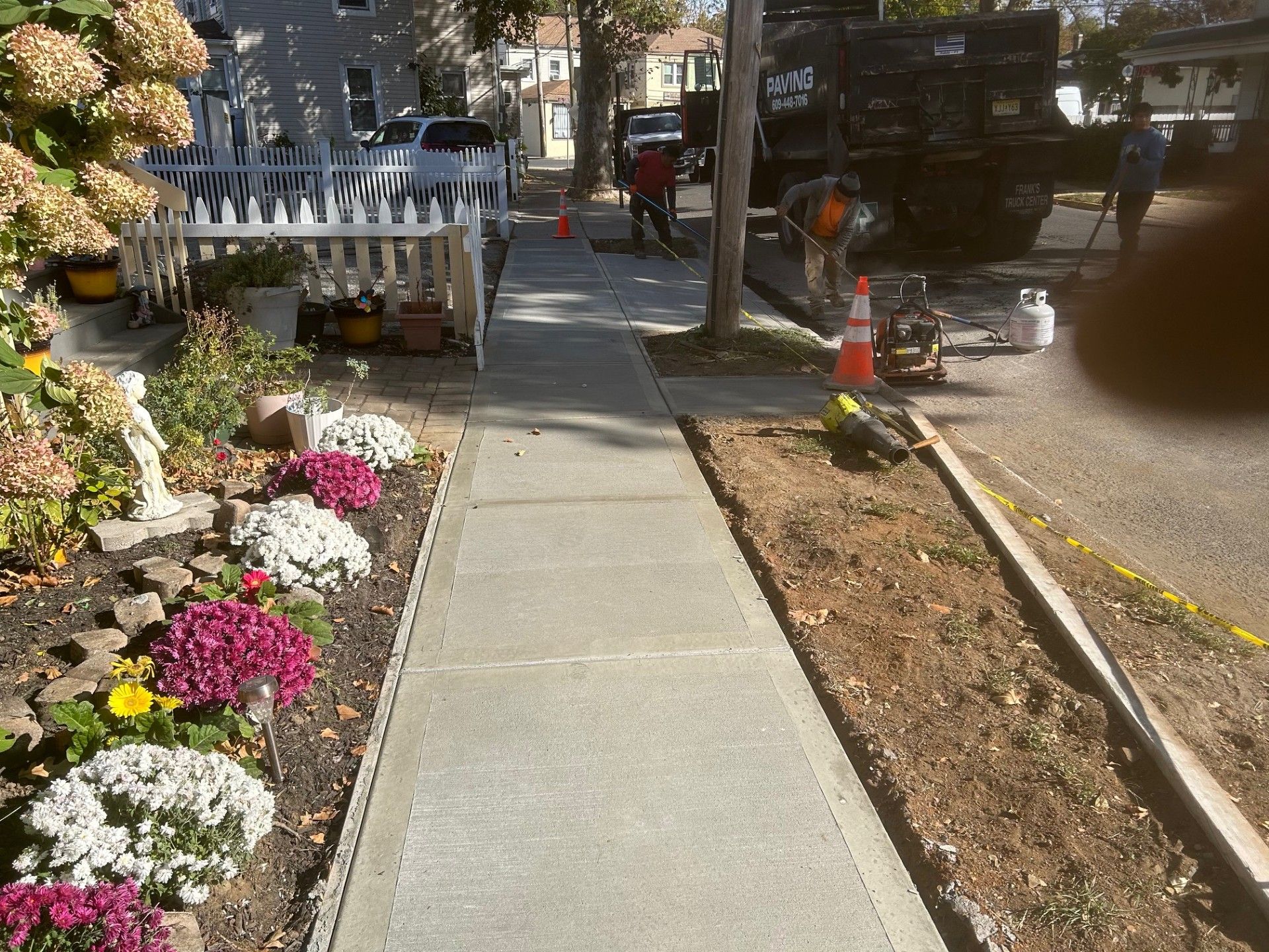 A sidewalk with flowers and a dump truck in the background