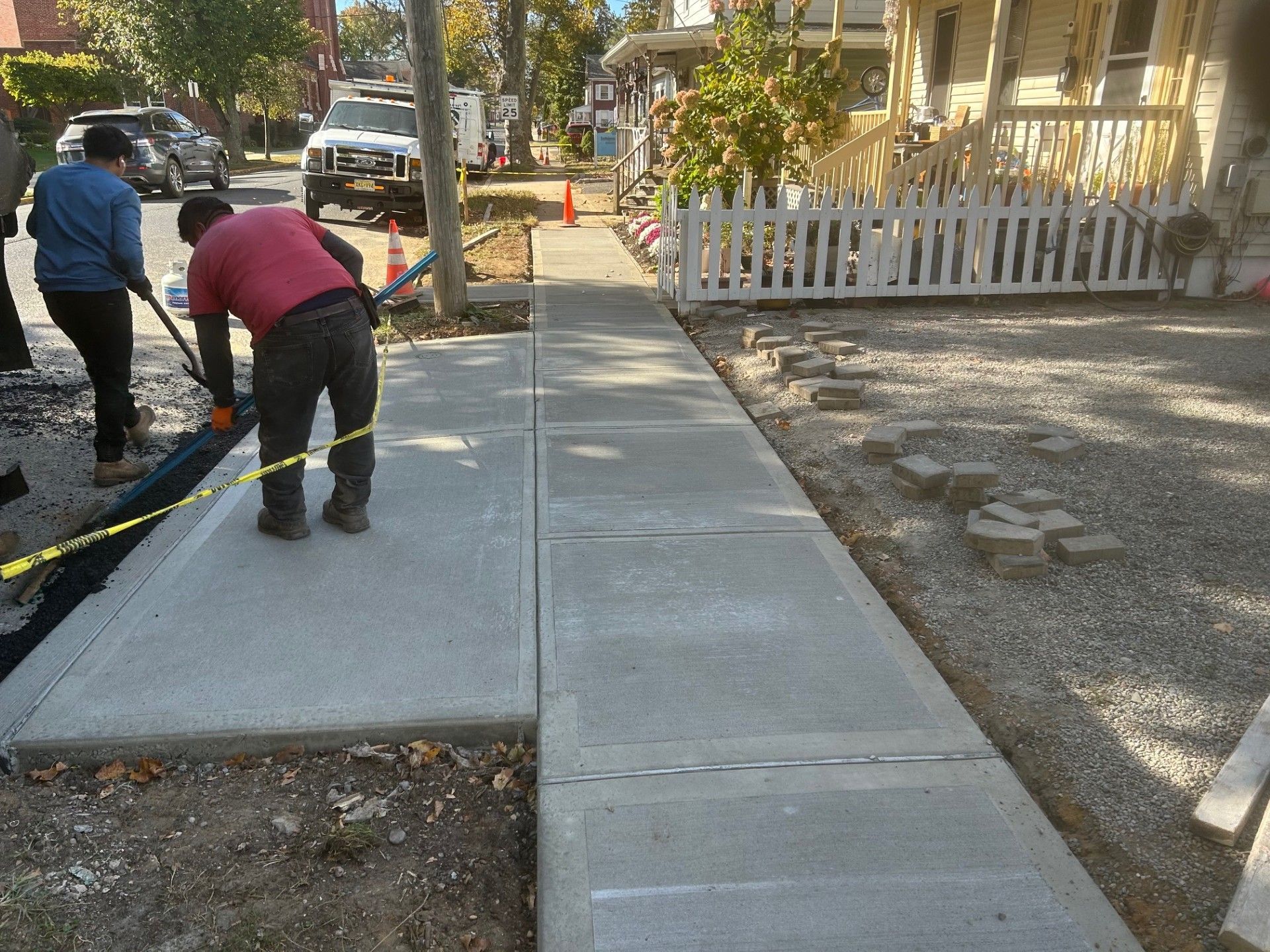 A man in a red shirt is working on a sidewalk.