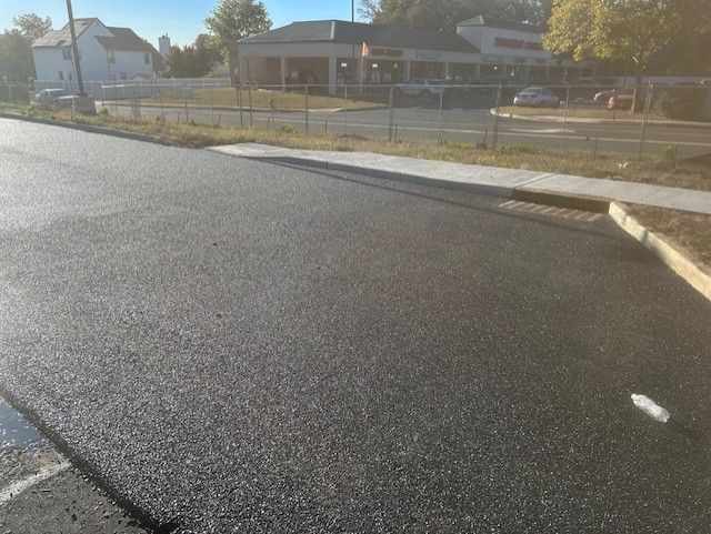 A road with a sidewalk and a building in the background.