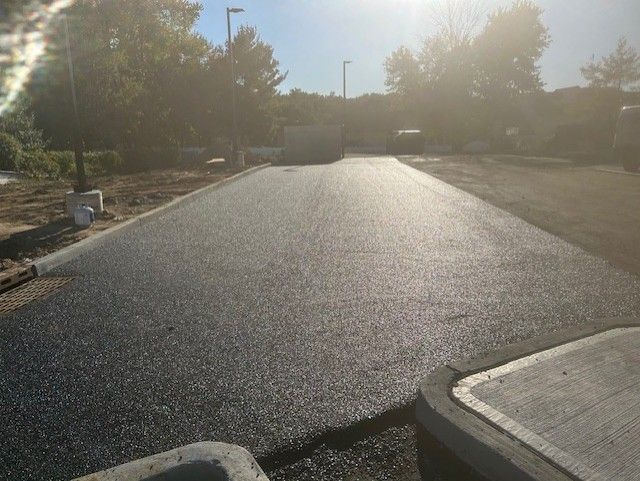 A road with a lot of asphalt on it and trees in the background.