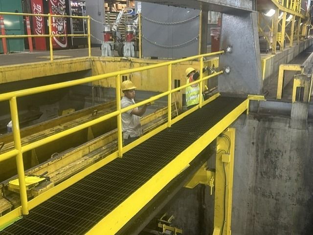 Workers are painting the indoor railings yellow.