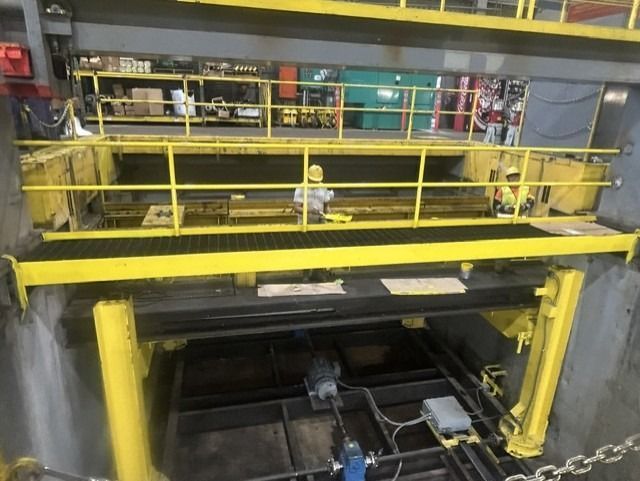 Workers are repainting the indoor railings in yellow.