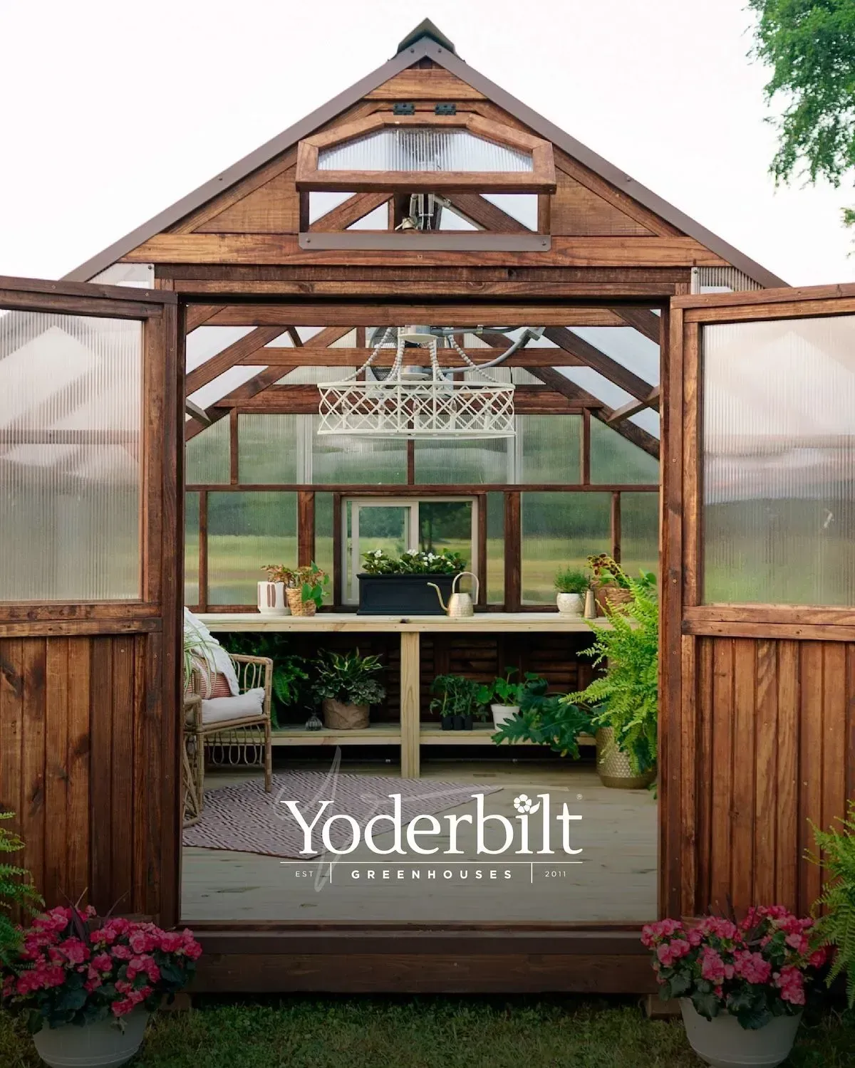 Wooden greenhouse with open doors, plants, and a workspace inside.