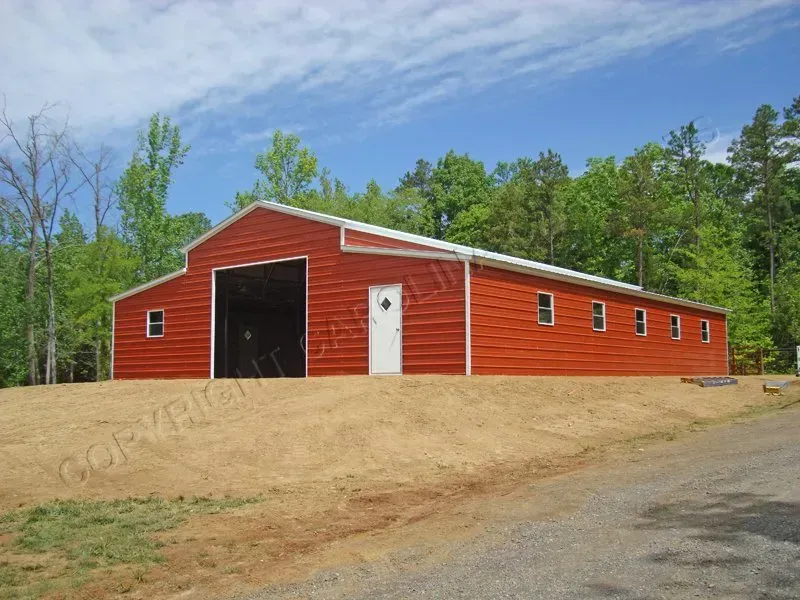 Red barn with black door, white door, and windows on a sunny day.