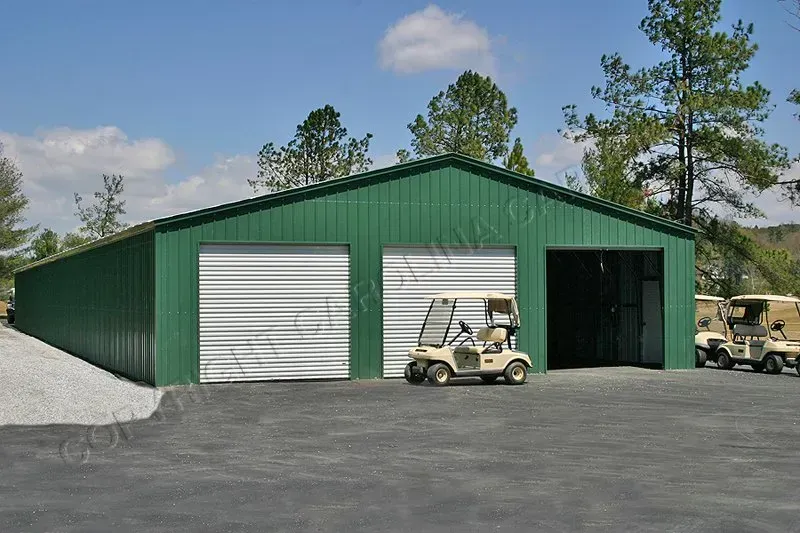 Green metal storage building with three bays. Two have closed roll-up doors, one open. Golf carts in front.