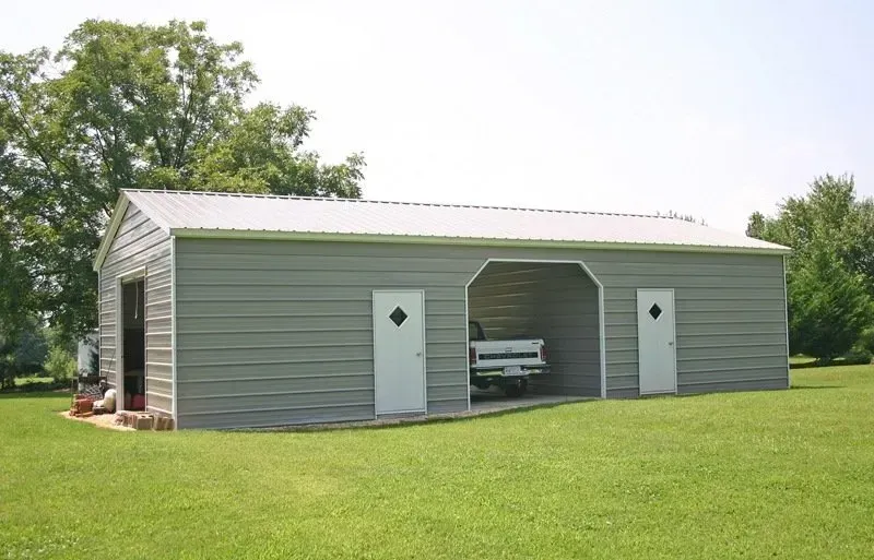 Gray metal garage with a car parked inside, two doors, and a green lawn.