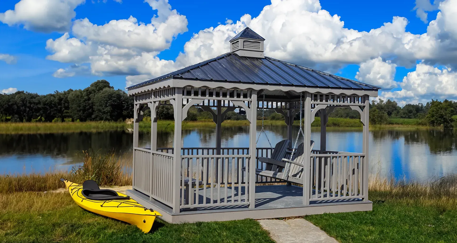 Gazebo with swing seating by a lake; yellow kayak at the edge.