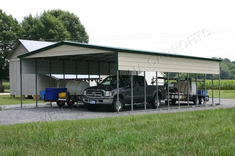 Green metal carport sheltering a black pickup truck and two trailers on a gravel driveway, with a small shed in the background.
