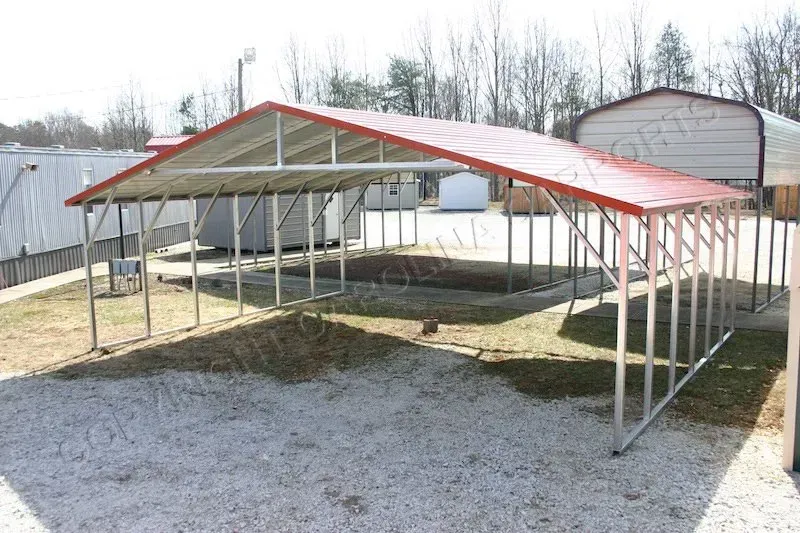 Metal carport with a red roof on a gravel surface.