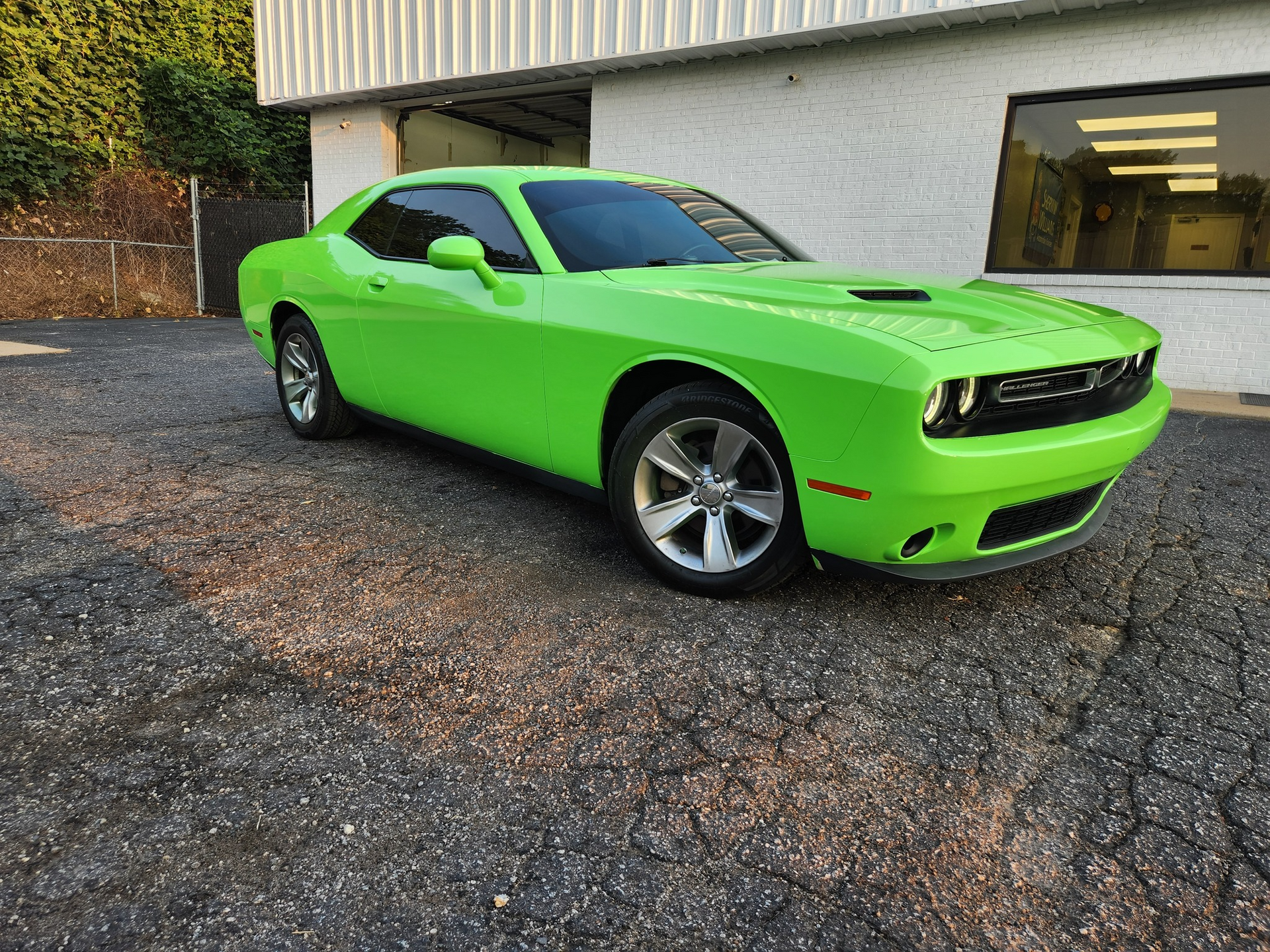 Green Dodge Challenger parked outside a building.