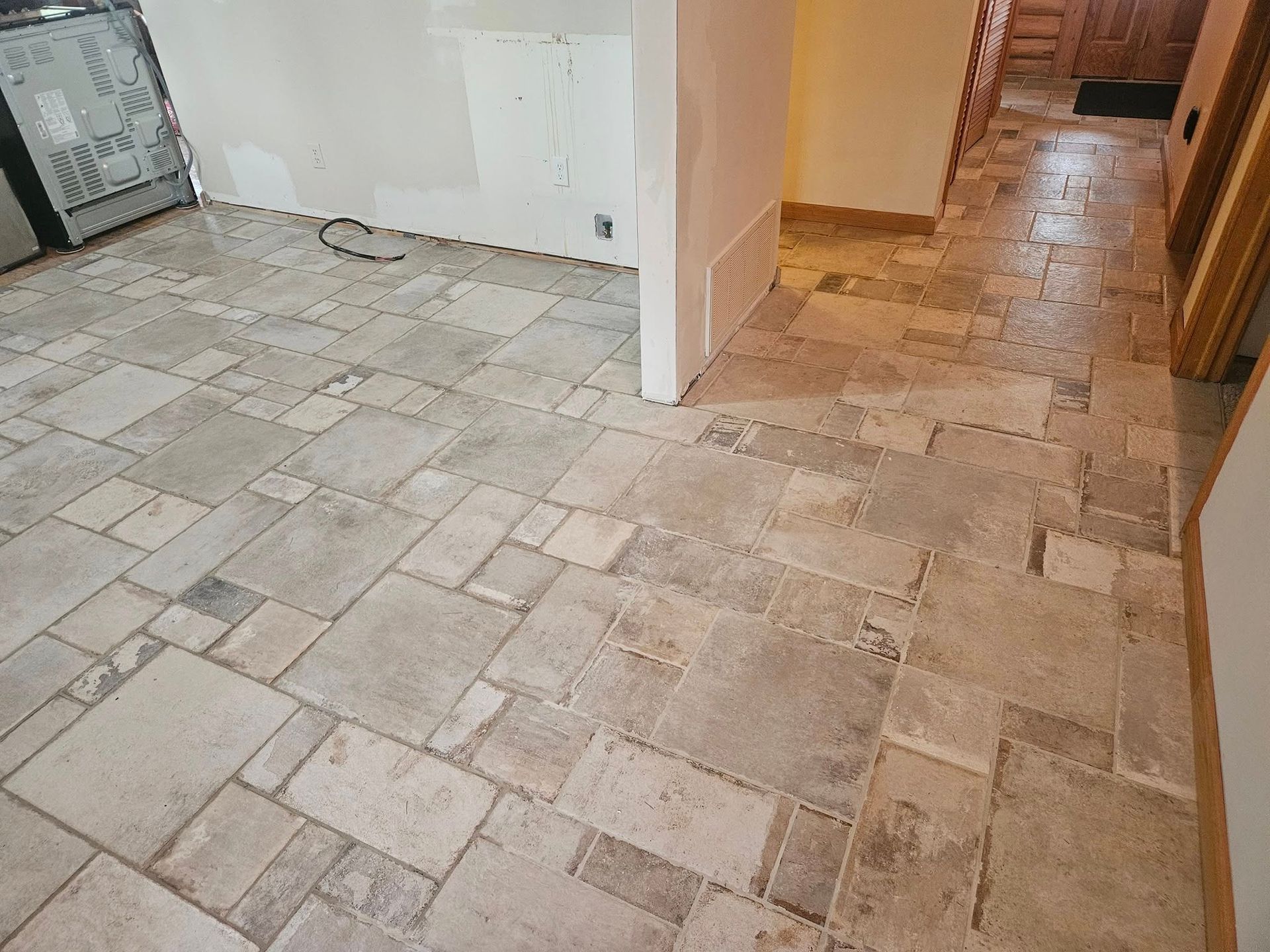 A wide-angle floor view of a room with beige and grey stone tiles arranged in a patterned layout.