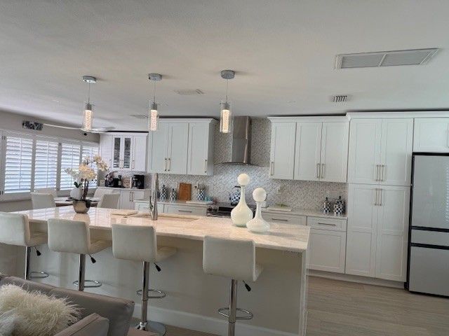 Modern white kitchen with island, cabinets, and stainless steel appliances. Bright, airy space with bar stools.