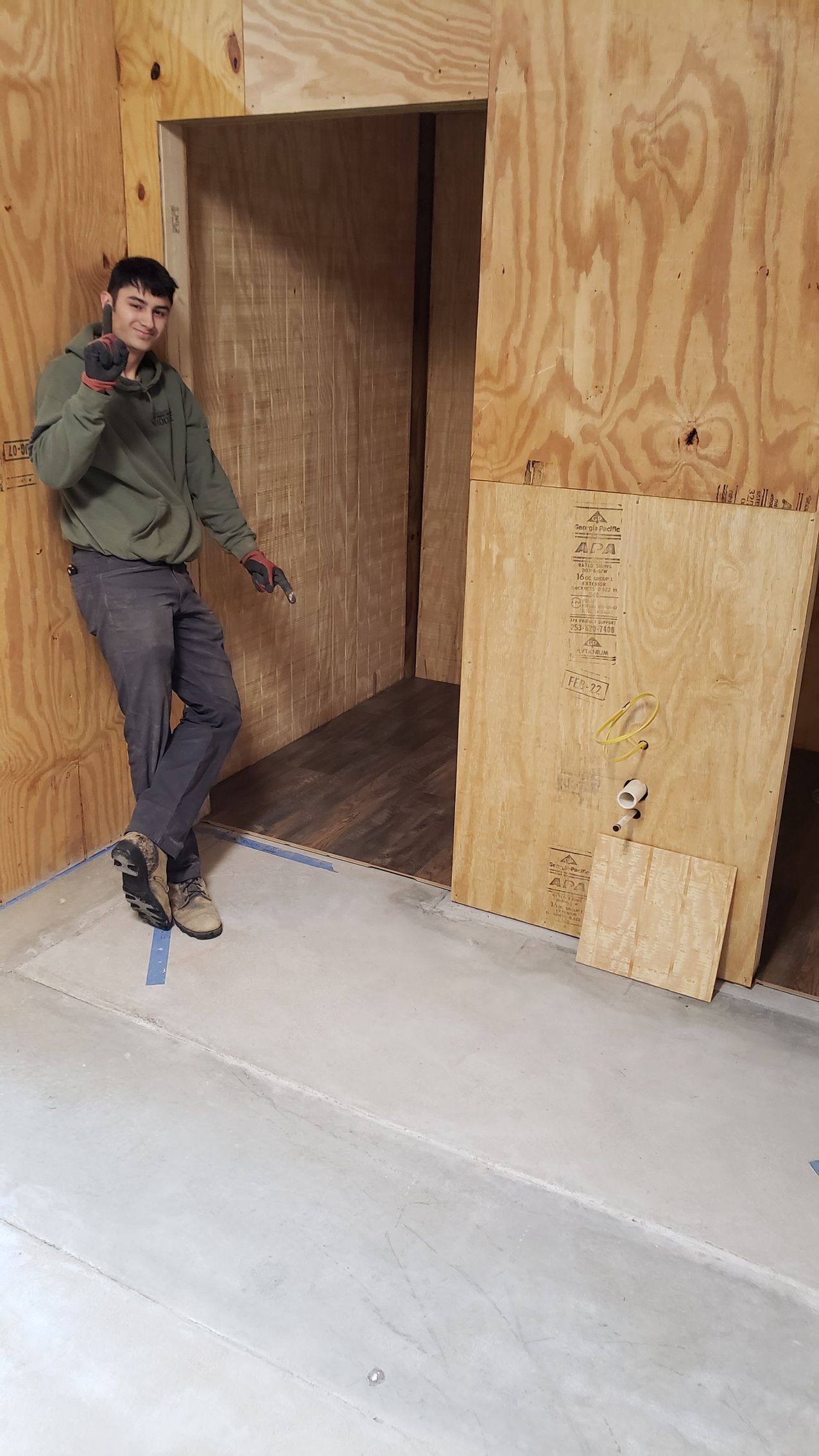 A paint roller is sitting on a red tray on a wooden floor.