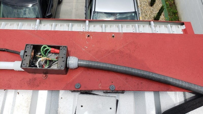 A hose is connected to a box on the roof of a building.
