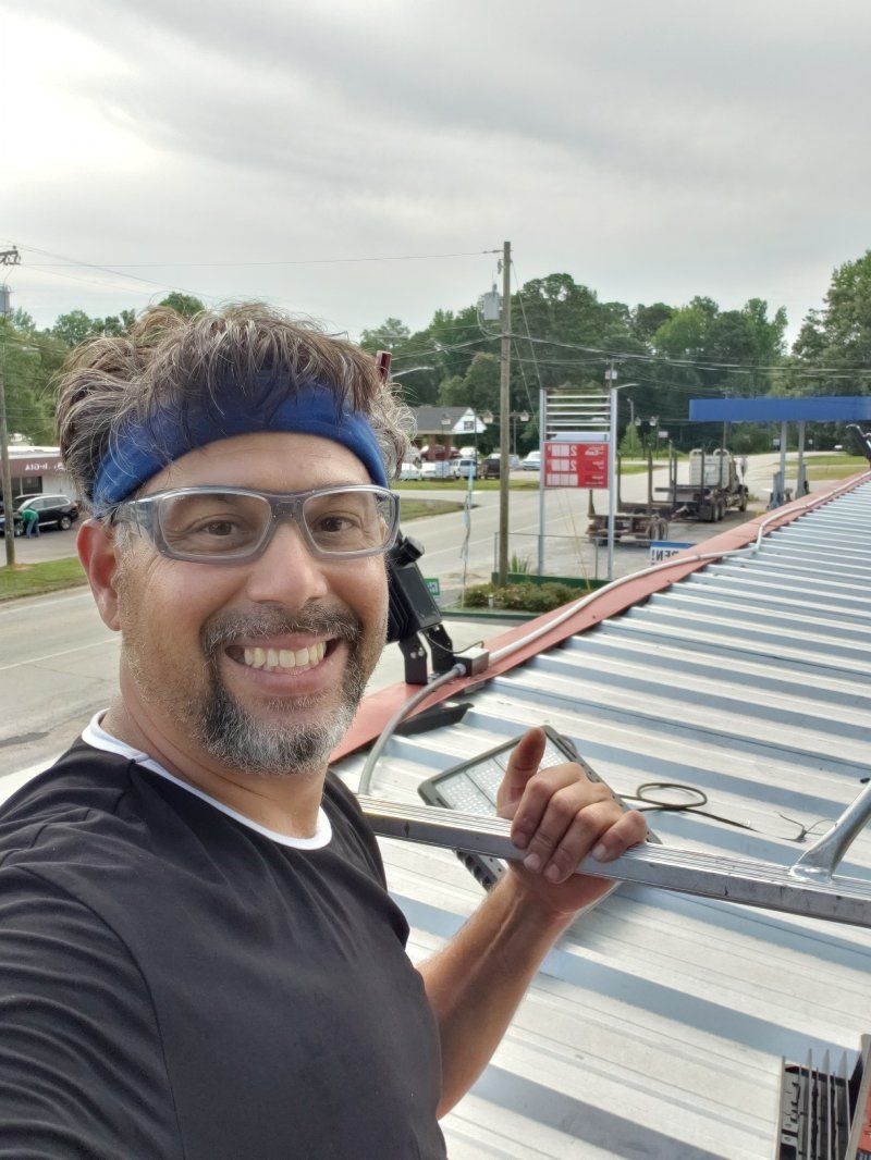 A man wearing glasses and a headband is standing on top of a metal roof.