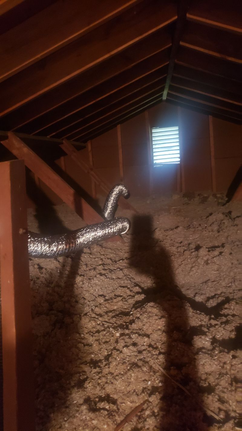 An attic with a window and a shadow of a person on the floor.