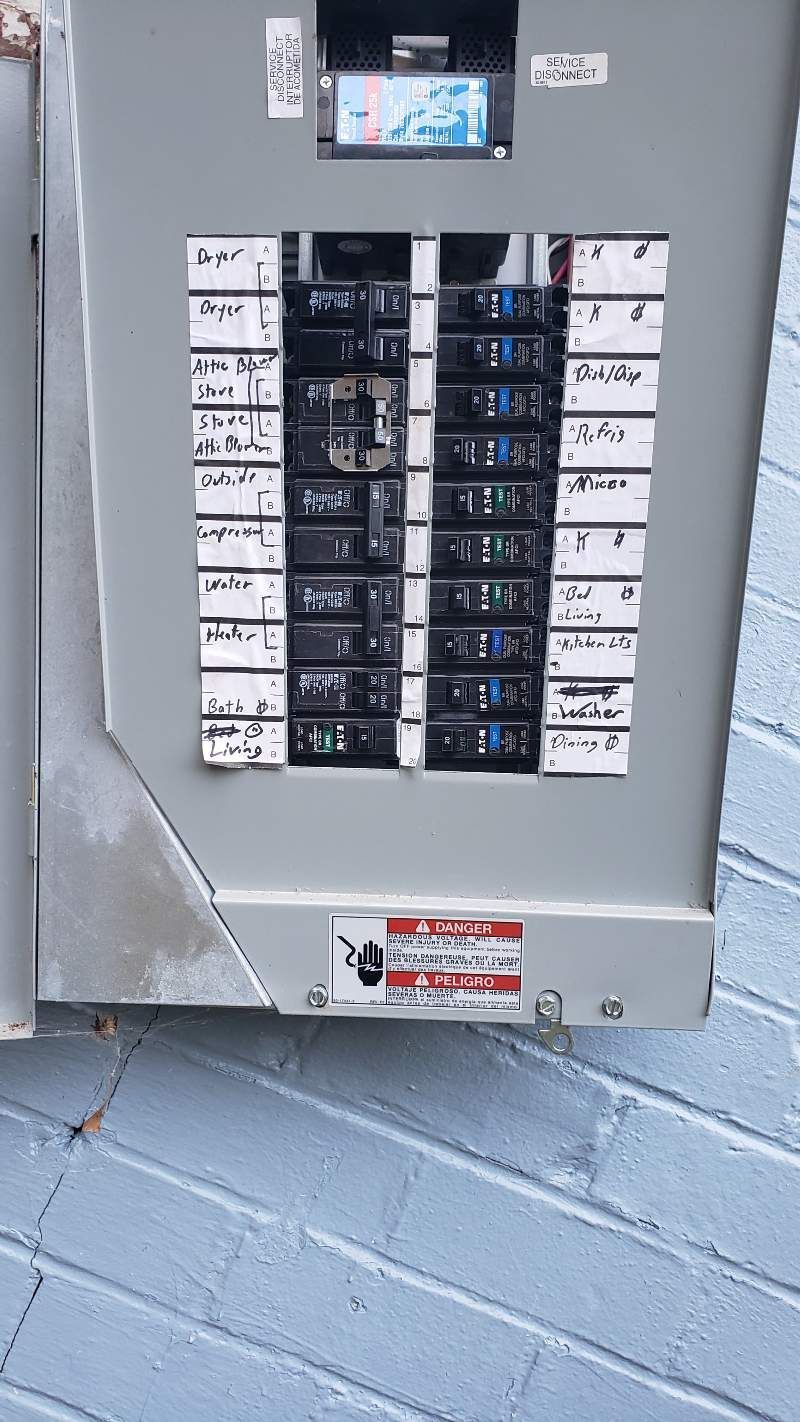 A gray electrical box is sitting on a blue brick wall.