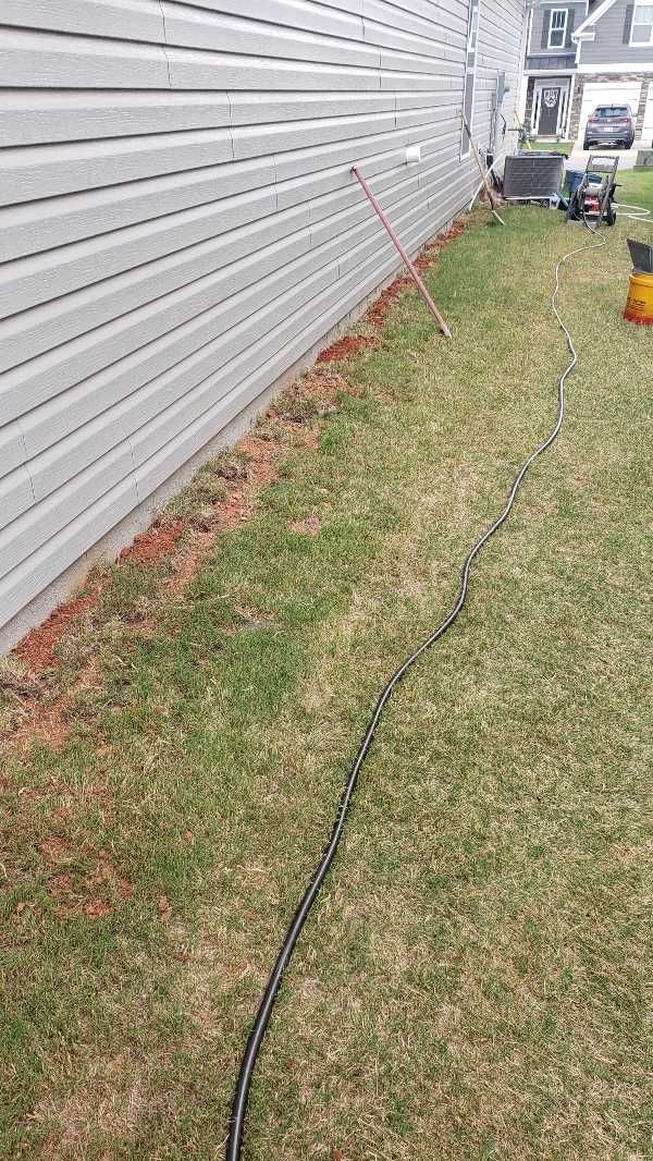 A hose is laying in the grass next to a house.