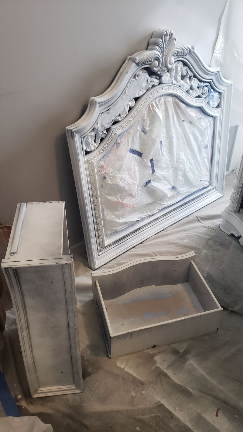 A mirror is sitting on top of a table next to a dresser and a drawer.