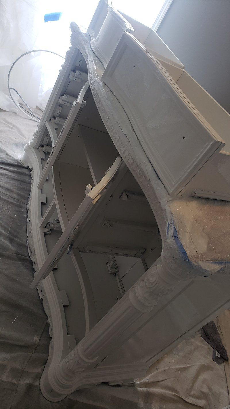 A white dresser is being painted in a room.