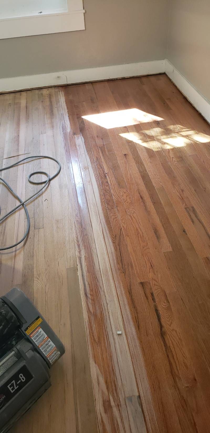 A vacuum cleaner is sitting on a wooden floor in a room.