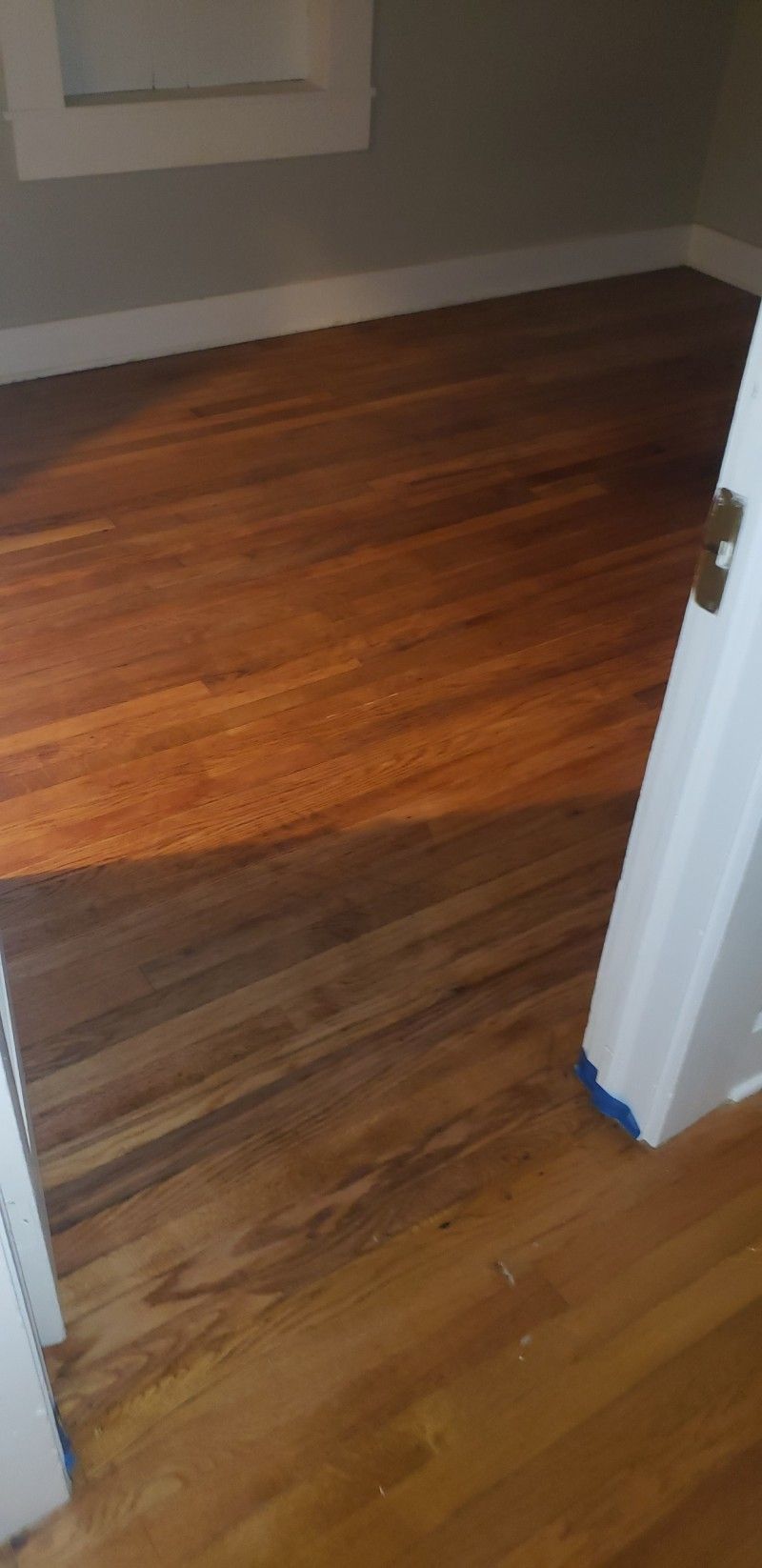 A wooden floor in a room next to a door.