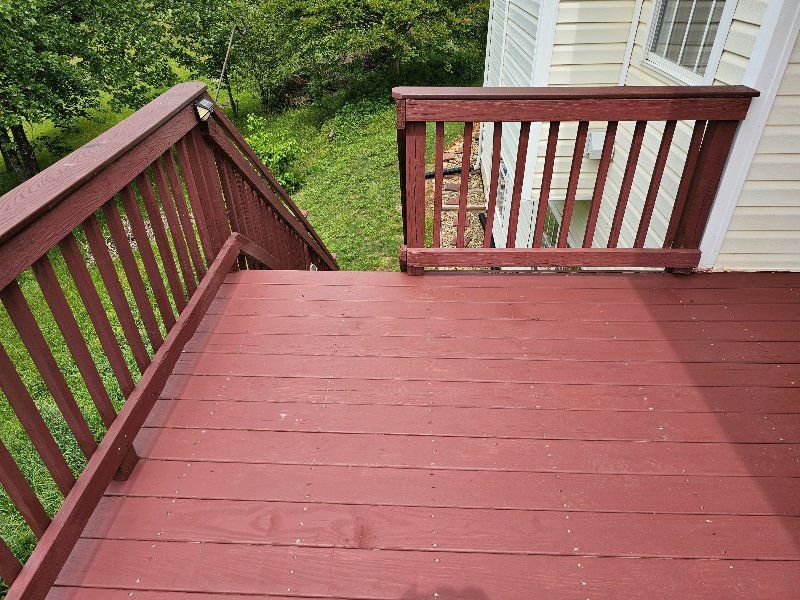 A red deck with a white railing and stairs leading up to it.