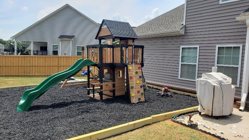 A backyard playground with a slide and climbing wall.