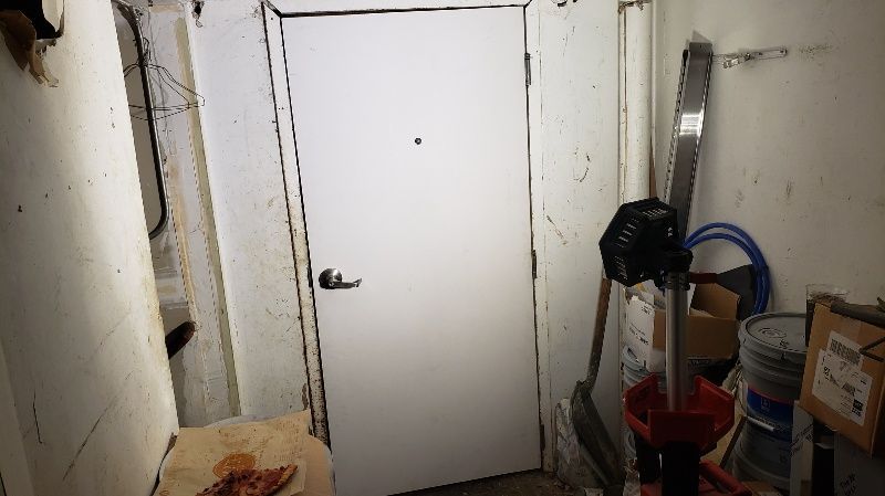 A room with a white door and a lot of junk in it.