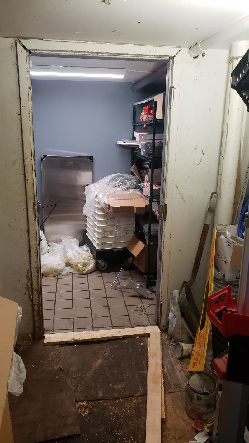 A room with a door open and a stack of pizza boxes on the floor.