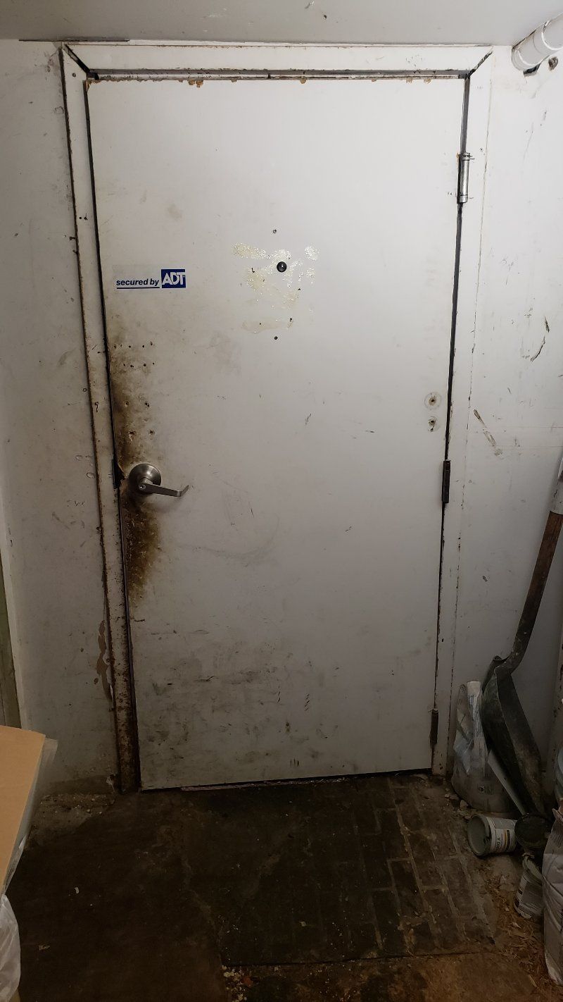 A white door is sitting in a dirty room.
