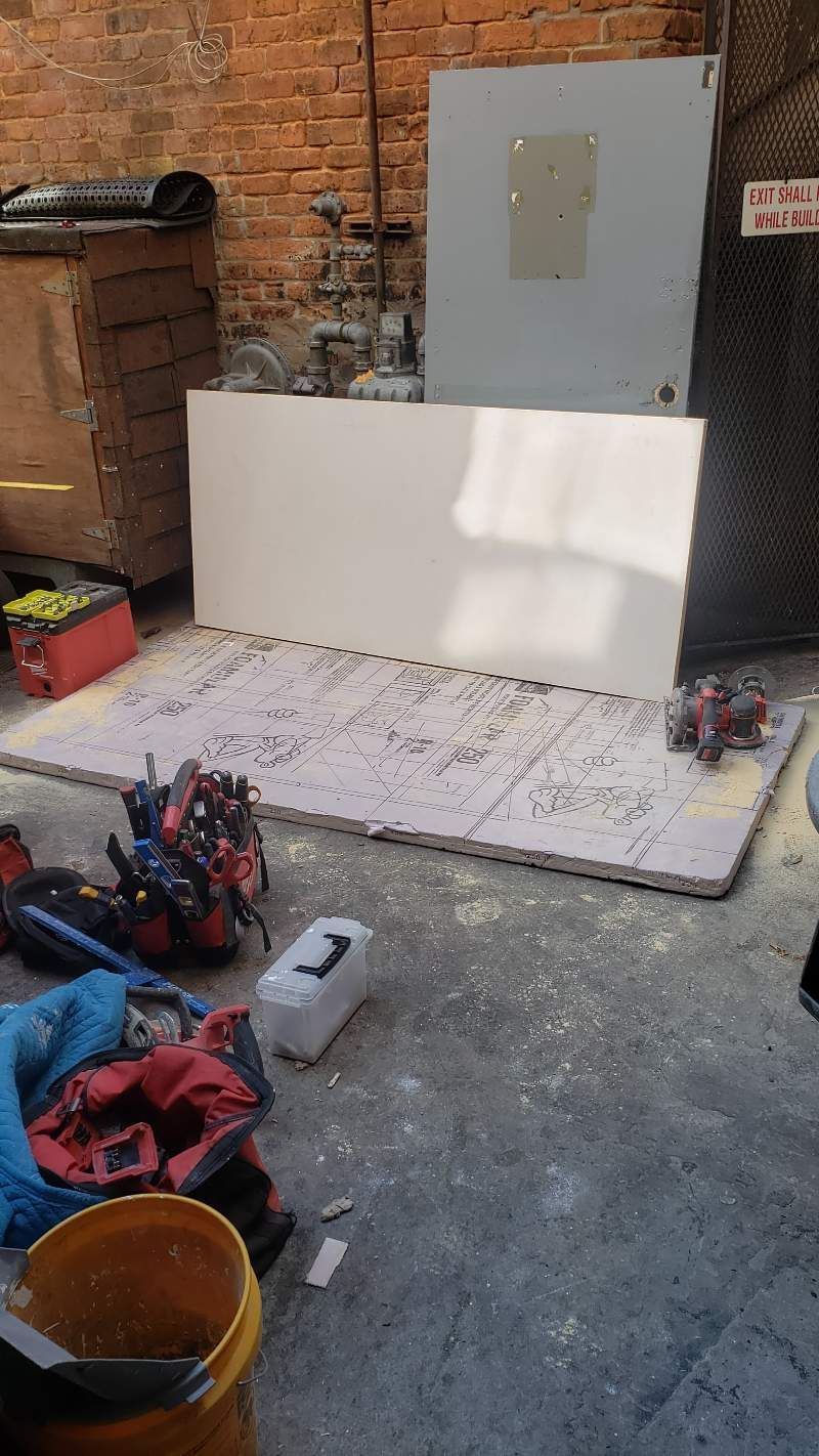 A bunch of tools are sitting on the ground next to a brick wall.