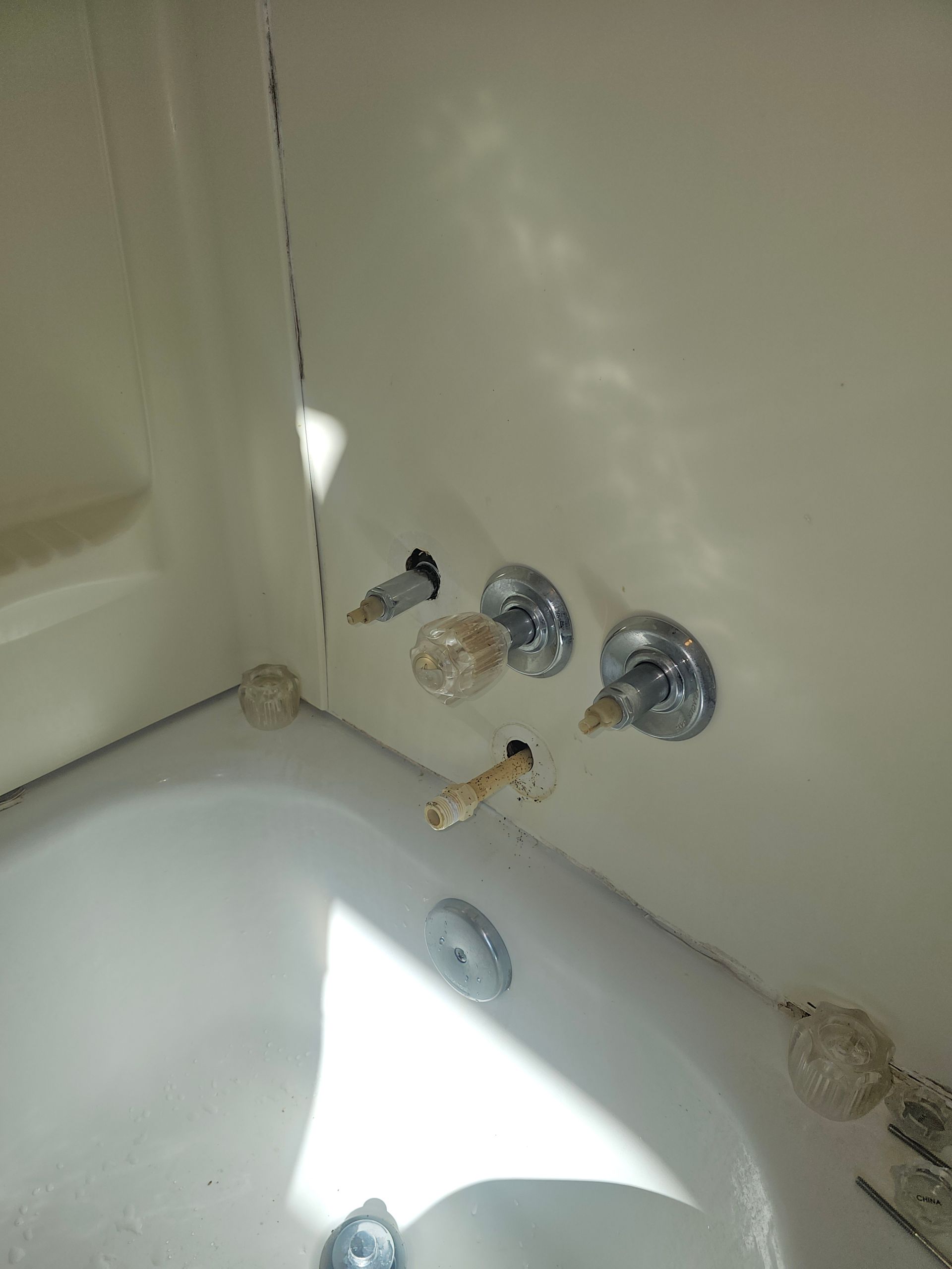 Bathtub with faucet handles; one handle is missing. White tub and walls.