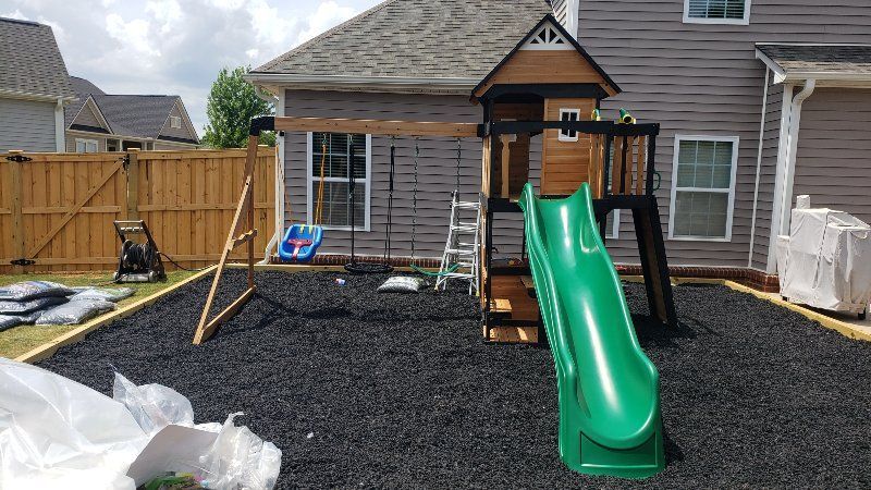 A backyard with a swing set and a slide in front of a house.