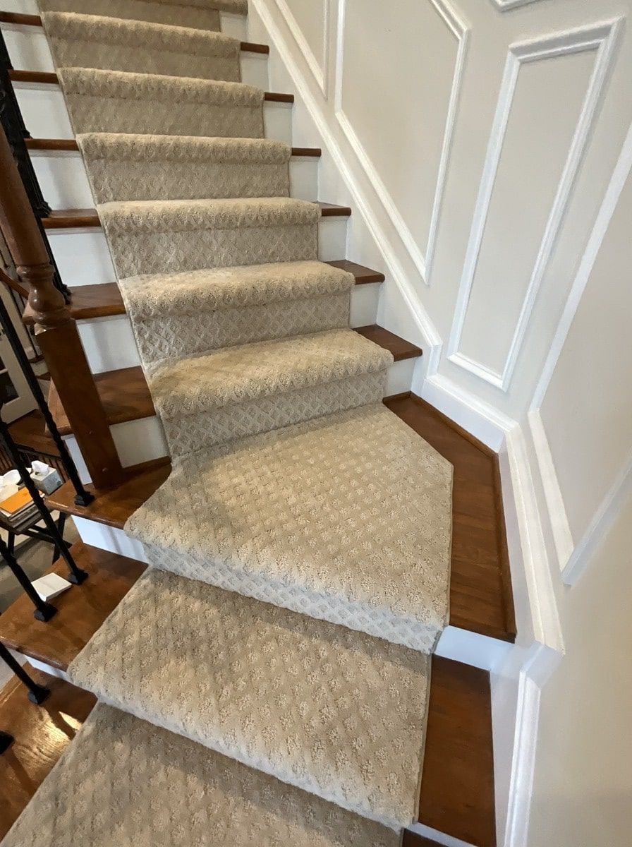 A staircase with a carpet on the steps and a wooden railing.