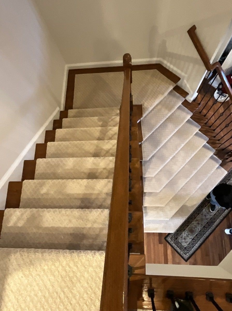 A staircase with a carpeted staircase and a wooden railing.