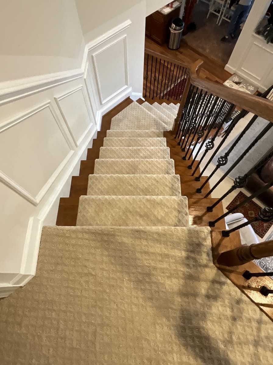 A staircase with a carpeted staircase and a wooden railing.