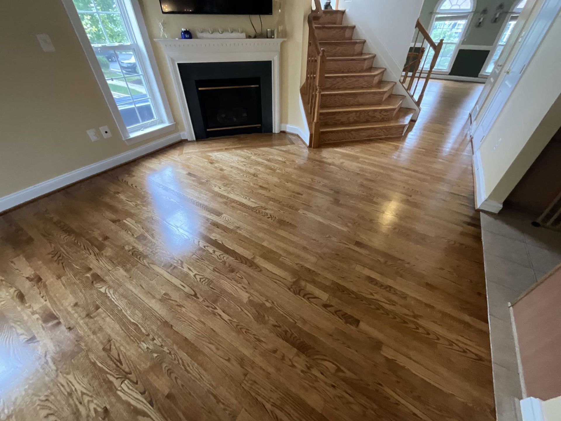A living room with hardwood floors , stairs and a fireplace.