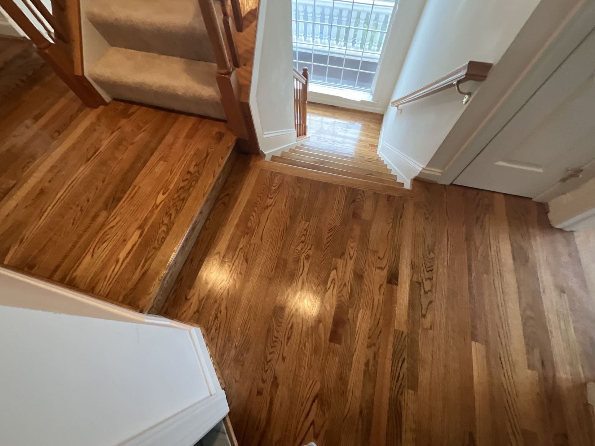A wooden floor in a room with stairs and a door.