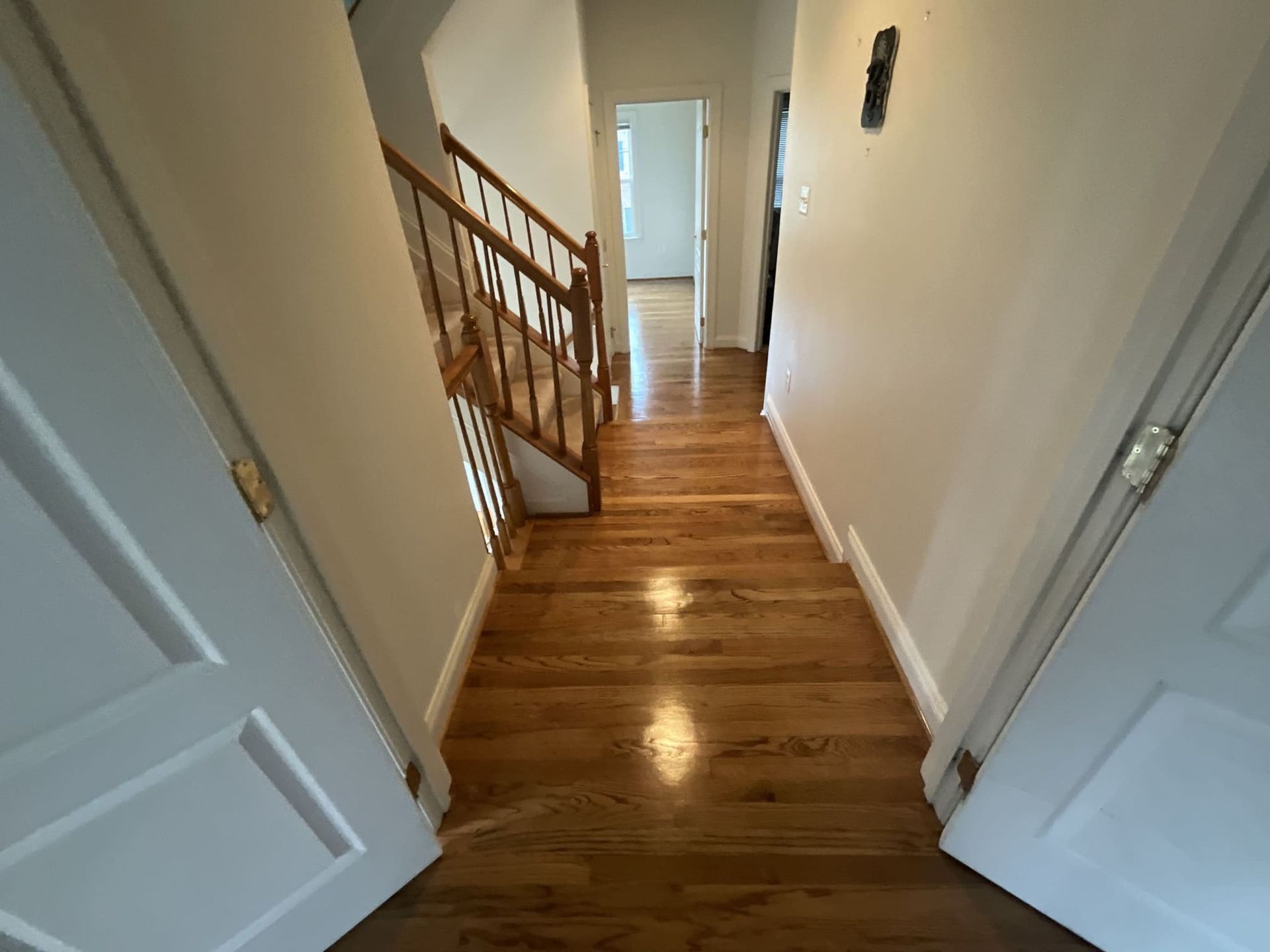 A hallway with hardwood floors and stairs in a house.