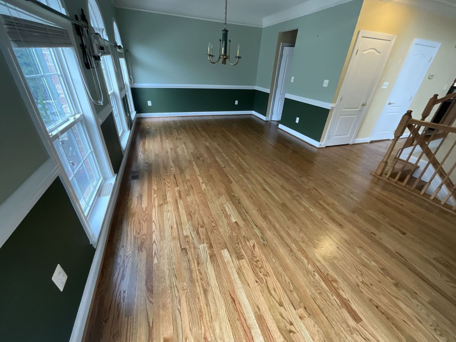 An empty dining room with hardwood floors and green walls.