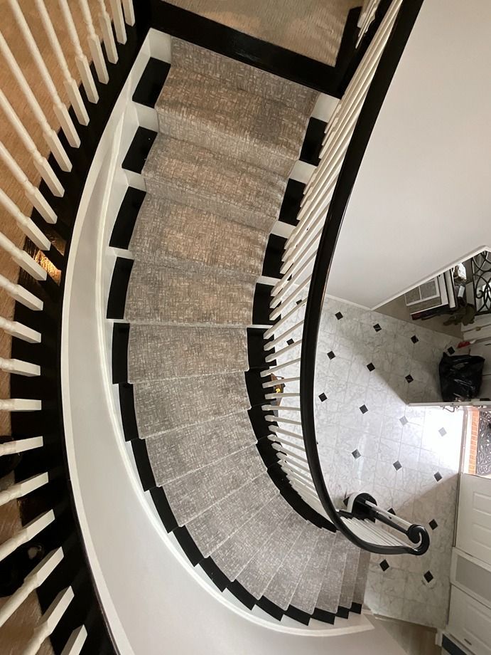 A spiral staircase with a black railing and a carpeted staircase.